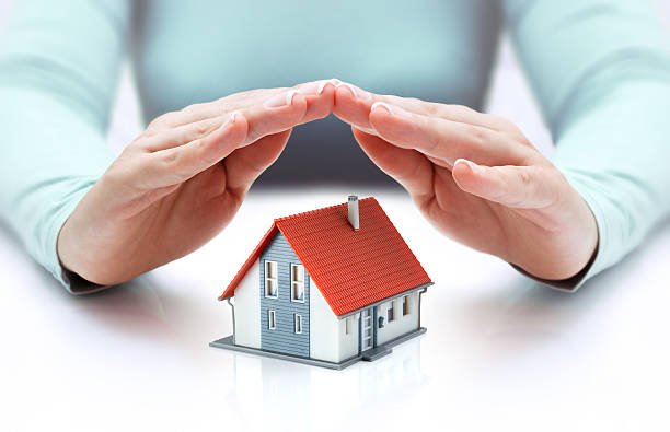 A pair of hands gently covering a small house, representing the security and protection provided by homeowners insurance.
